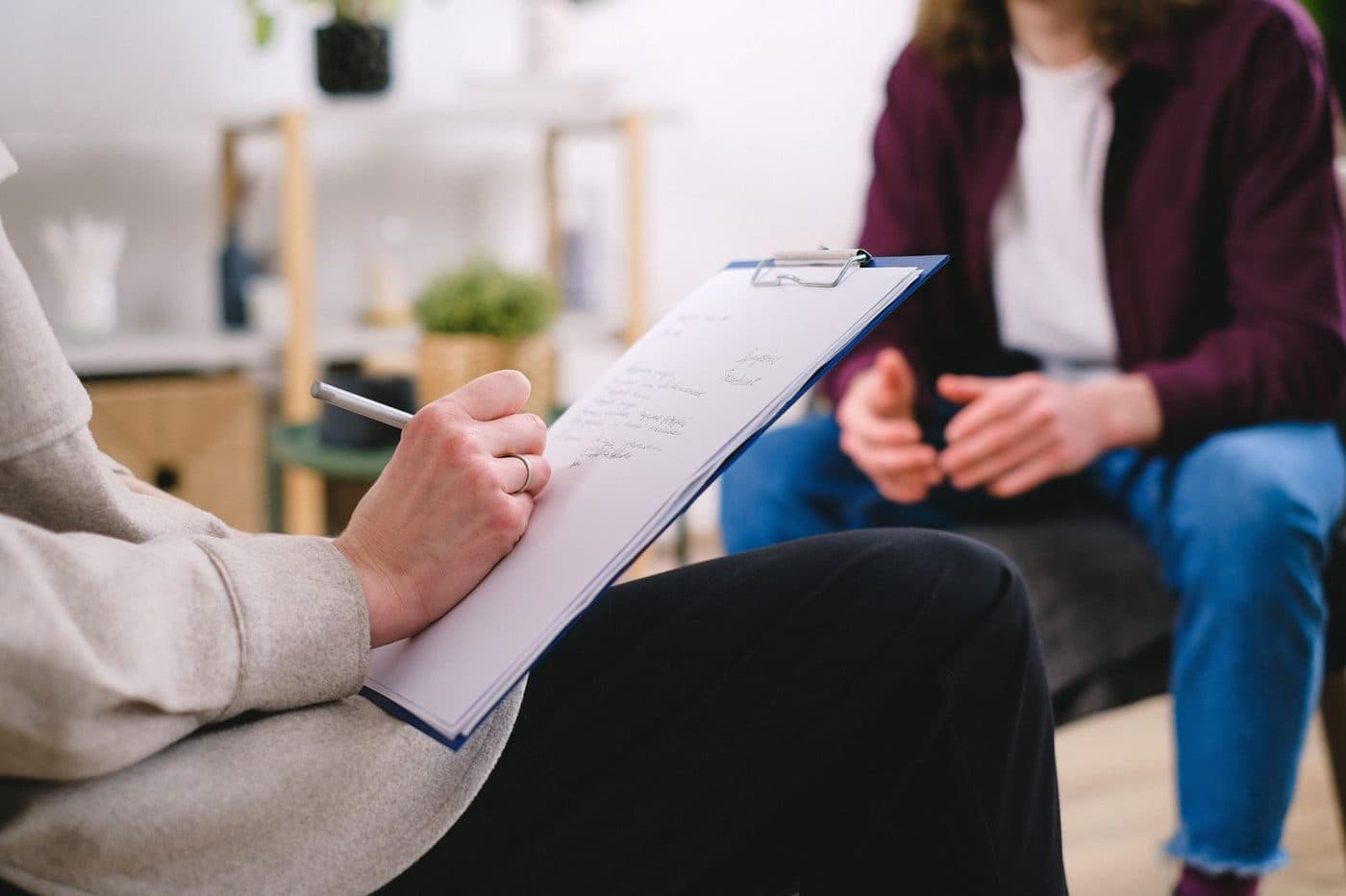 Close-up of a clinician writing notes on a clipboard during an appointment